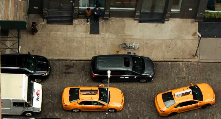 Overhead photo of bright yellow NYC cabs maneuvering through a narrow street in Soho.